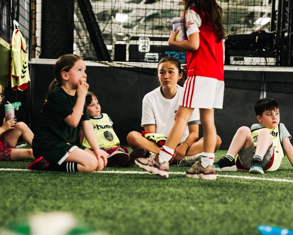 Des jeunes enfants en tenues de soccer se rassemblent sur un terrain de gazon intérieur pendant une séance d'entraînement
