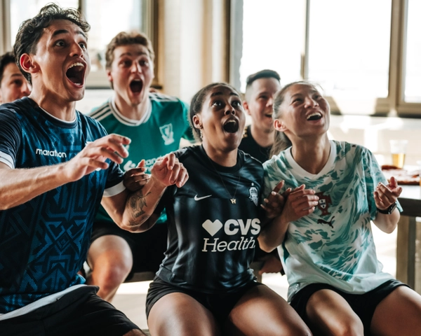 Un groupe de fans de soccer en maillots d'équipe célébrant un moment excitant, manifestant de la joie et de l'enthousiasme