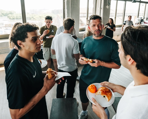 Un groupe de membres d'une équipe de soccer socialisant et mangeant des pâtisseries dans un salon de bureau lumineux et