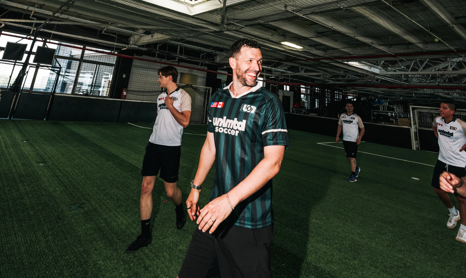 Des joueurs en tenue sportive sur un terrain de soccer intérieur à l'installation d'entraînement Unlimited Soccer avec gazon